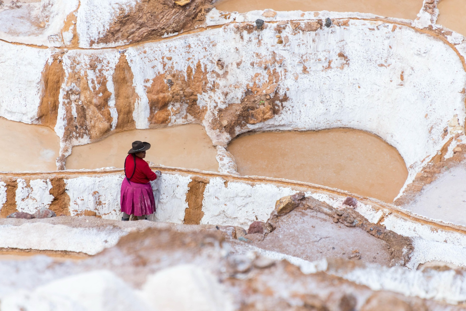 A local harvester gathering salt by hand at the Maras terraces